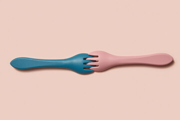 Pastel blue and pink kid forks on beige background