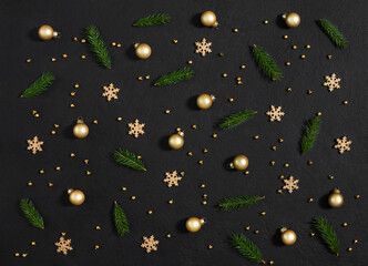 Christmas pattern with fir branches, golden baubles and snowflakes on ablack background. New Year composition. Greeting card. Top view, flat lay.