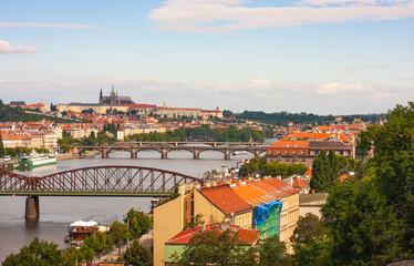 Prague castle and St Vitus Cathedral in distance up the hill. See panorama view of bridges and Vltava River. Railroad bridge is in foreground..