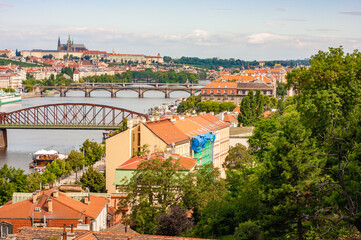 Fototapeta na wymiar Prague castle and St Vitus Cathedral in distance up the hill. See panorama view of bridges and Vltava River. Railroad bridge is in foreground..