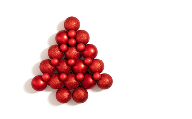 Christmas red baubles laid out in the shape of a Christmas tree. New Year decorations isolated on a white background. Top view, flat lay.