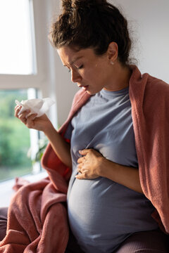 Pregnant woman sneezing at home