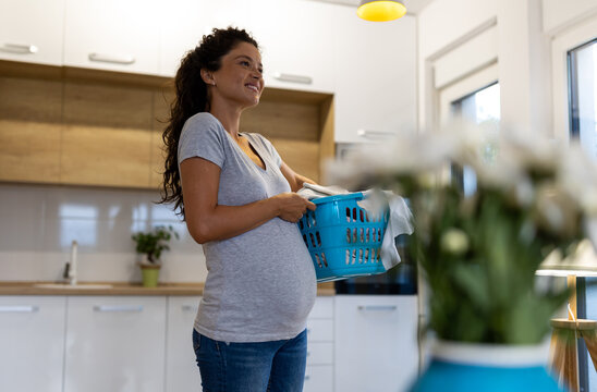 Pregnant woman carrying laundry at home