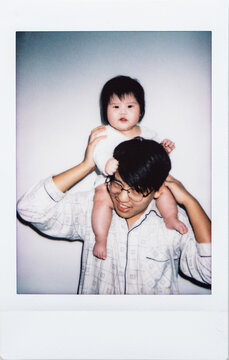 Polaroid photo of father carring newborn baby girl on his shoulders