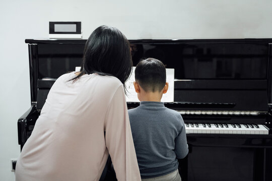Mother and son playing piano at home

