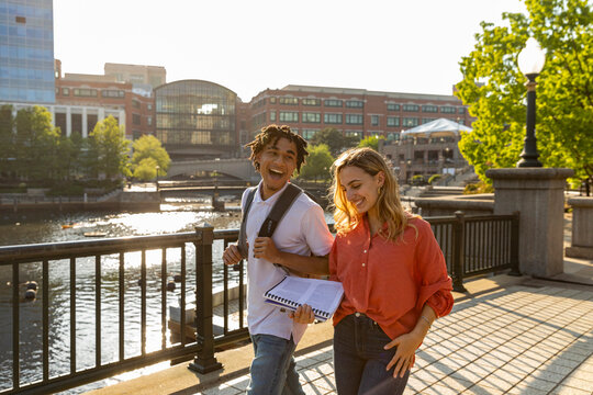 Two cute Friends University Students carry books on campus 