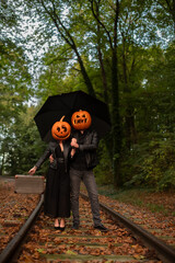 Paar mit geschnitzten Kürbis auf dem Kopf, Regenschirm und Koffer auf reisen