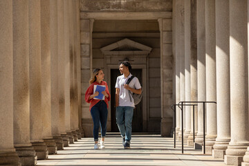 Two Friends University Students walk in campus hallway outdoors 