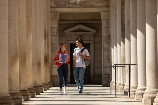 Two Friends University Students walk in campus hallway outdoors 