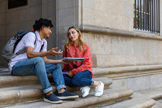 Confused University Students review assignment in hallway 