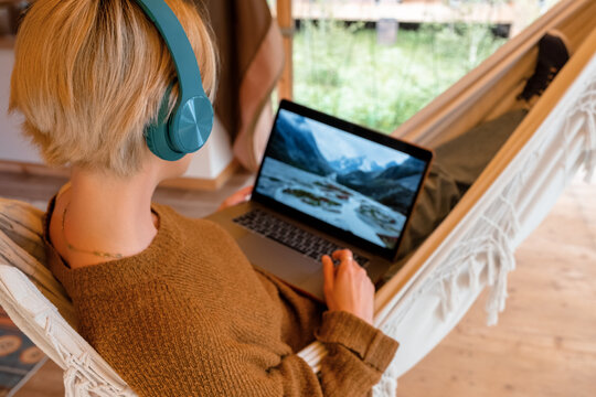 Anonymous woman chilling in hammock and watching video