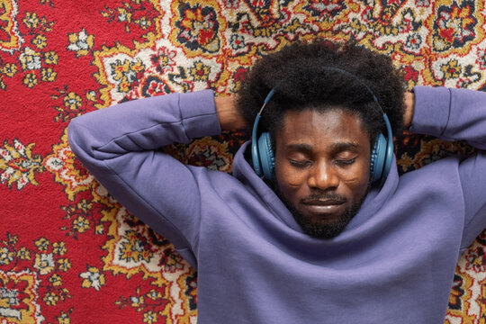 Black male listening to music on carpet