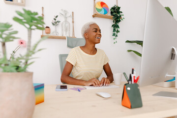 Joyful black woman typing on computer in workplace