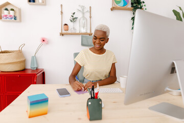 Smiling black woman writing on sticky note in office