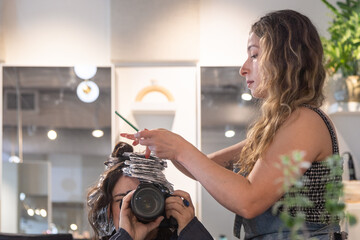 Photographer shooting stylist in salon through mirror