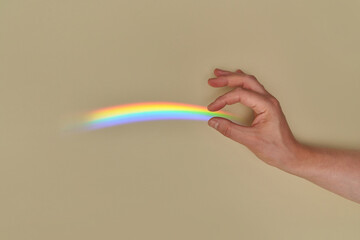 Person holding rainbow reflected on wall.