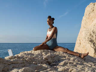 Black female during online yoga lesson near sea