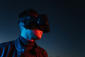 Young man in VR glasses against evening sky