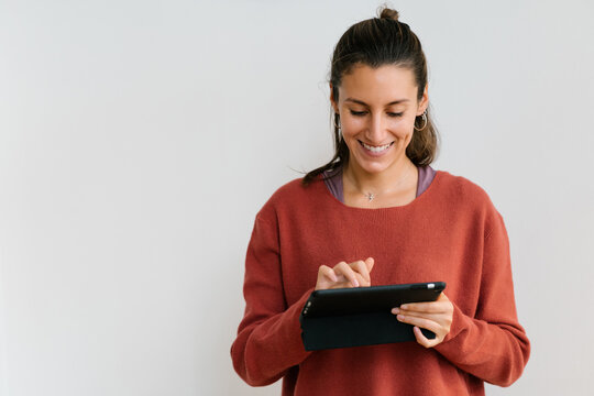 Smiling woman browsing tablet near wall