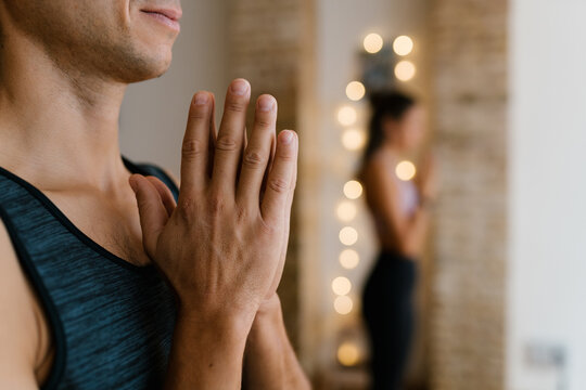 Unrecognizable man meditating with prayer hands