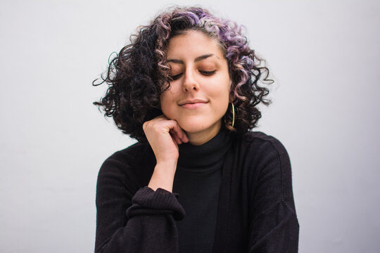 Latina woman with curly hair and closed eyes
