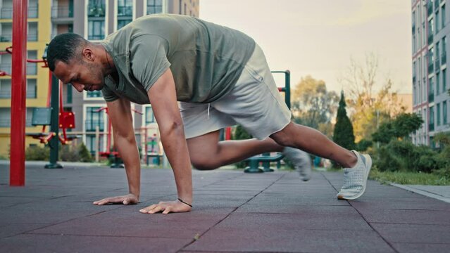 Slender fit man in sportswear doing plank run workout in morning sportswoman running on spot pulling legs to chest from push ups position fitness exercises outdoor for body strength interval training