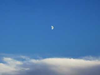 Luna bianca calante nel cielo azzurro sopra le nuvole