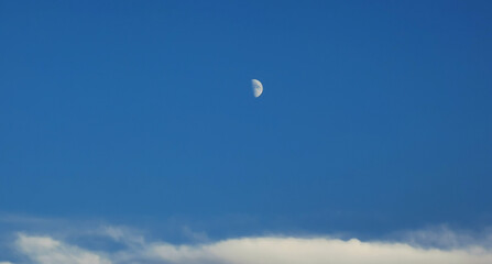 Luna bianca calante nel cielo azzurro sopra le nuvole
