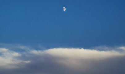 Luna bianca calante nel cielo azzurro sopra le nuvole