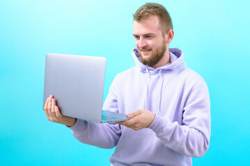 Surprised man looking on laptop display on the blue background. Caucasian. Symbol. Cyberspace. Executive. Indoor. Notebook. Success. Workplace. Office. Work. Young. Male. Worker