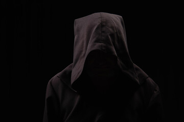 medieval monk with face under dark hood isolated on black.