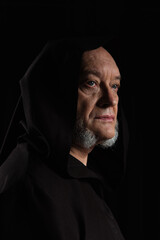 portrait of medieval monk in hooded robe isolated on black.