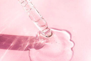 Transparent facial serum pipette on pink background. Soft focus. Cosmetic Beauty product closeup.