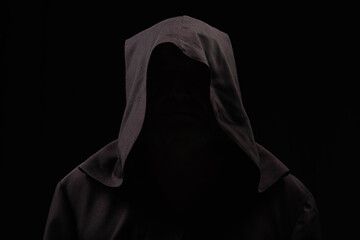 mysterious anonymous monk in dark hood isolated on black. - obrazy, fototapety, plakaty