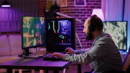 Handheld shot of gamer streaming fast paced space shooter on gaming pc setup while explaining gameplay to subscribers. Caucasian man playing multiplayer online action game talking to team on headset. © DC Studio