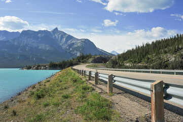 Fototapeta na wymiar Abraham lake in the mountains of Alberta shown from metal barrier against asphalt highway travel holiday 