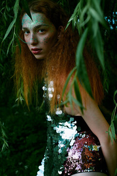 Beautiful red-haired model posing in foliage