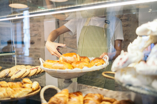Saleswoman in a pastry shop placing the buns on the counter