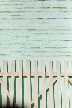 white wooden fence leaning against a pastel-colored brick wall