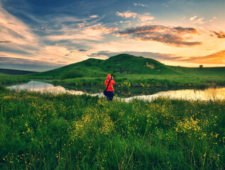 Fototapeta na wymiar woman on the banks of the picturesque river. tourist is enjoying the morning landscape. colorful spring sunrise