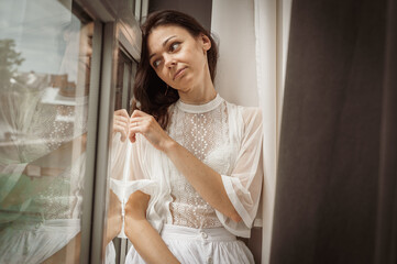 Fototapeta premium young pretty, emotional girl sits by the window. Waiting, looking for someone.