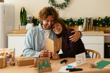 Beloved couple reading card and smiling during Xmas