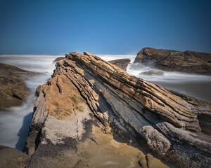 Stones on the beach sand with waves on it.