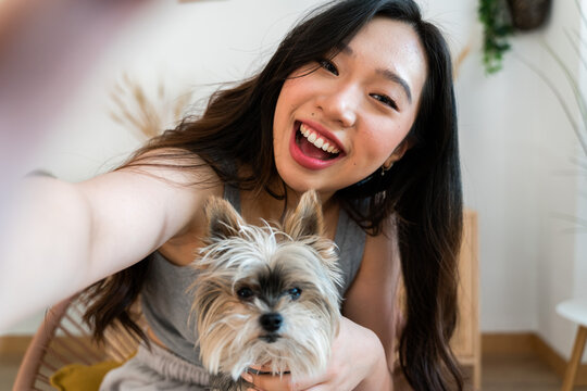 Smiling woman taking a selfie with her dog at home.