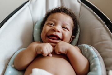 Adorable baby boy laughing in a bouncer