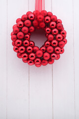 Shiny red christmas wreath on white wood copy space