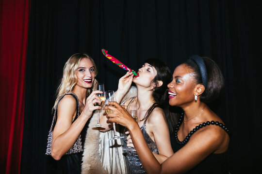 Trendy ladies clinking champagne glasses during party