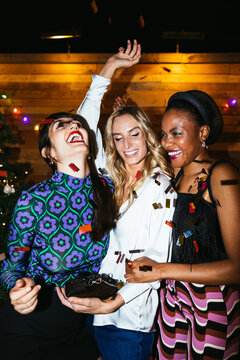 Diverse girlfriends throwing confetti in air
