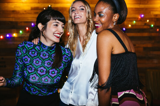 Cheerful multiracial women hugging during party