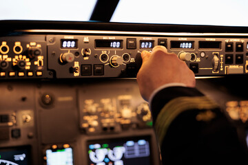 Male captain fixing altitude and longitude level on dashboard in plane cockpit. Pilot pushing...